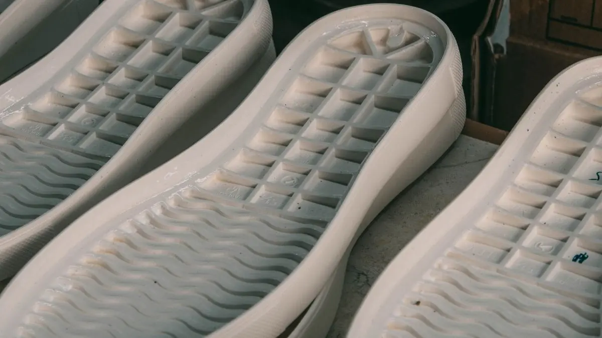 Close-up of white footwear sole units showing their inner surfaces and raised structural details.