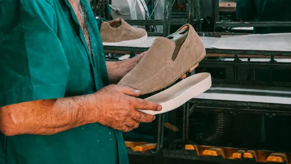 Footwear specialist aligning a detached outsole with a lasted suede slip-on prototype