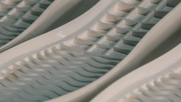 LG Shoes - Custom outsole tooling: when should footwear brands invest in a custom sole? 3 Detailed view of white sole units with raised inner ribs and textured sidewalls.